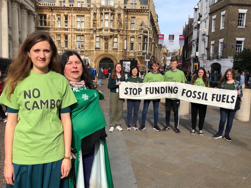 Activist Hannah and Councillor Naomi stand with protestors holding a banner reading 'stop funding fossil fuels'