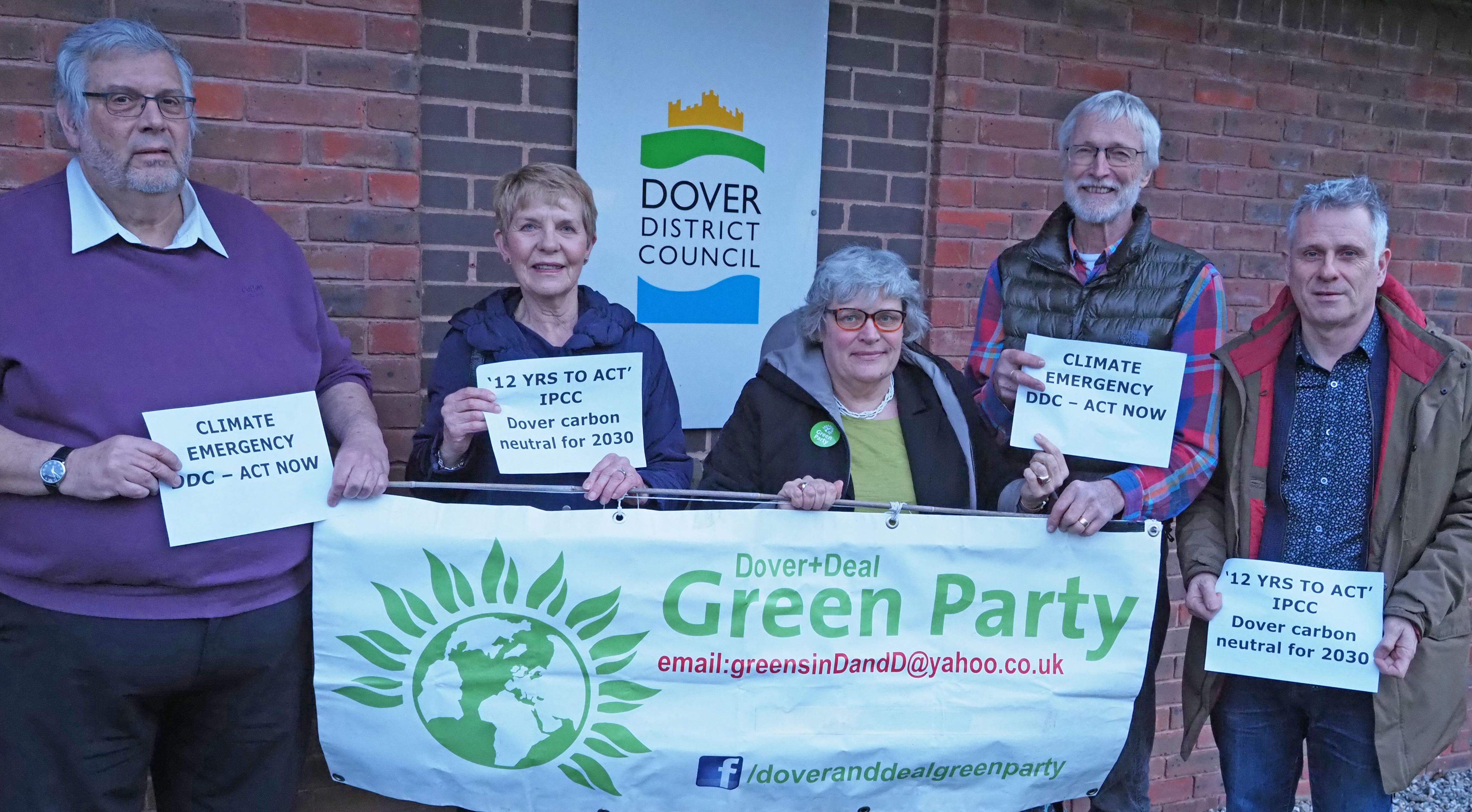 Green party members holding up signs stating '12 years to act', 'Climate emergency', 'Dover Carbon Neutral for 2030', 'Act Now'.