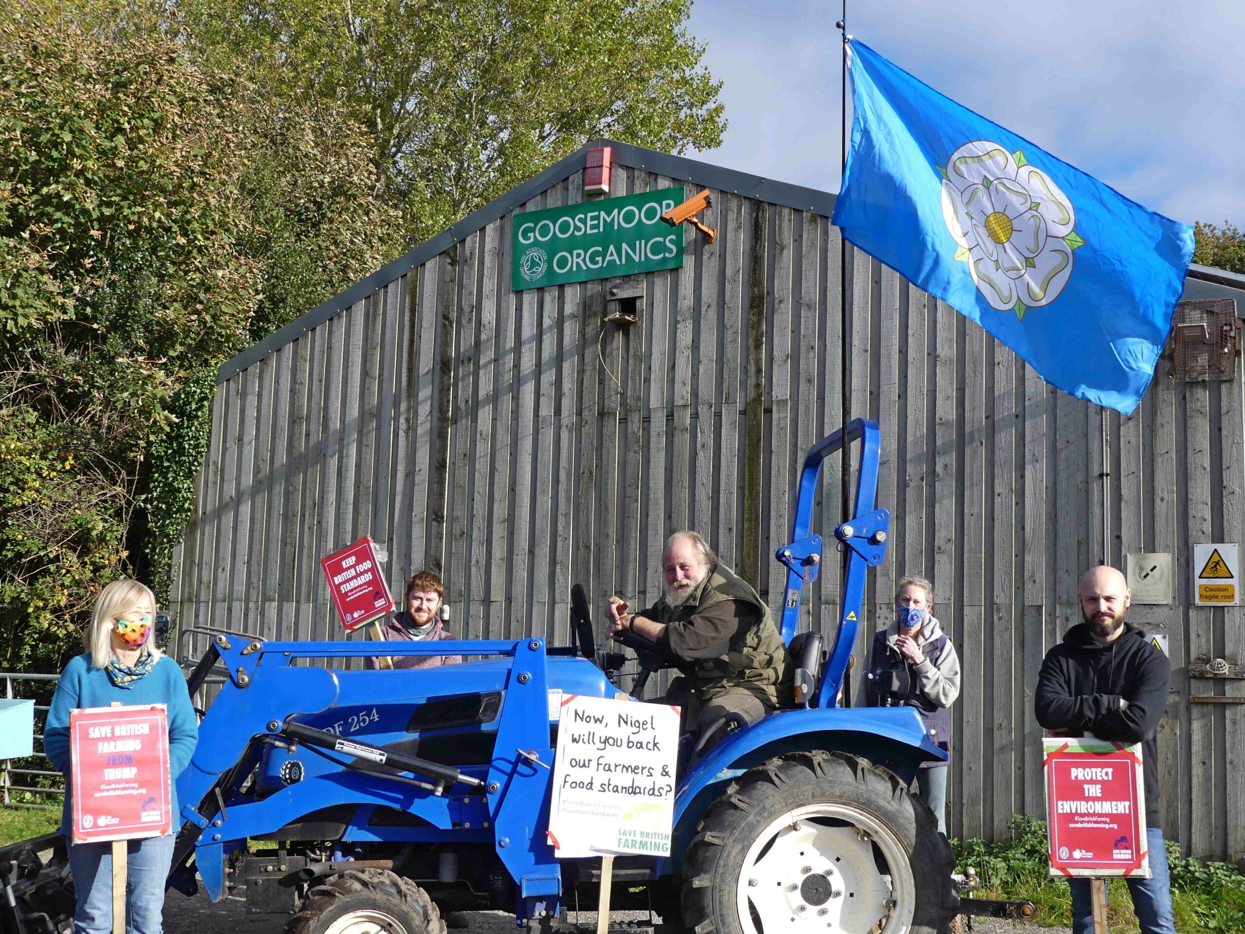 From left to right: Lorraine Meehan, Gordon Schallmo, Arnold Warneken, Alex Marsh, and Tom Bellerby outside Goosemoor Organics in Cowthorpe, with a Yorkshire flag and Save British Farming posters, including a large poster asking Nigel Adams to 'back our farmers and food standards'.